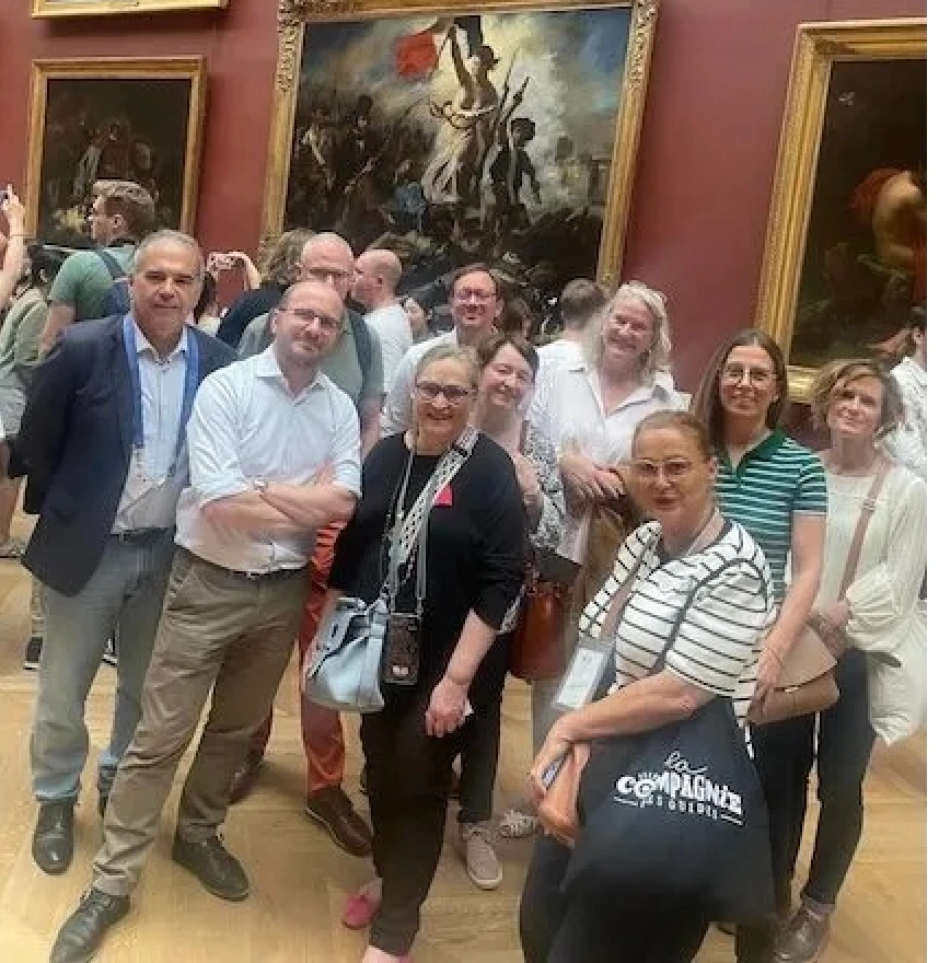 A group with their guide in front of Liberty Leading the People at the Louvre